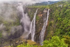 Jog Falls cascading down a tall rocky cliff surrounded by green forest