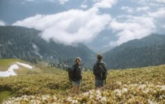 Backpackers walking with large backpacks along a scenic route in Japan, enjoying budget travel exploration.