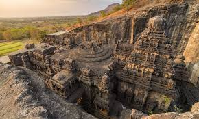 Intricate stone carvings and pillars inside an ancient Indian rock-cut cave temple.