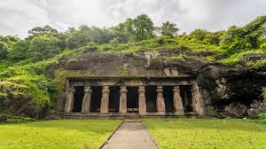 Intricate rock-cut cave temple with carved pillars, sculptures, and ancient stone architecture in India.